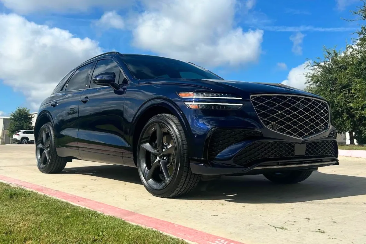 Blue Genesis GV70 SUV parked outdoors with clear skies