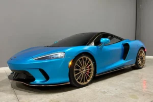 Blue vinyl wrapped McLaren parked inside a detailing shop.