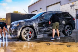 Black SUV covered in soap during car detailing service