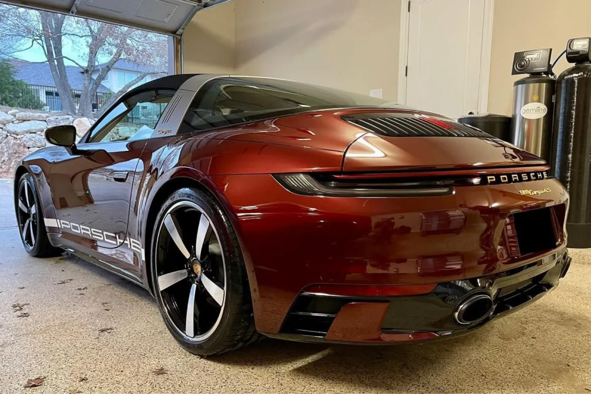 Red Porsche with vinyl wrap applied, showing glossy finish in a garage setting.