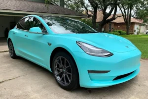 Front side view of a Tesla finished with a turquoise vinyl wrap.